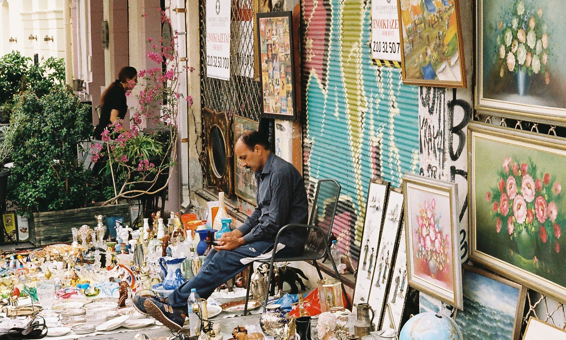 A busy outdoor flea market with tables of secondhand goods.