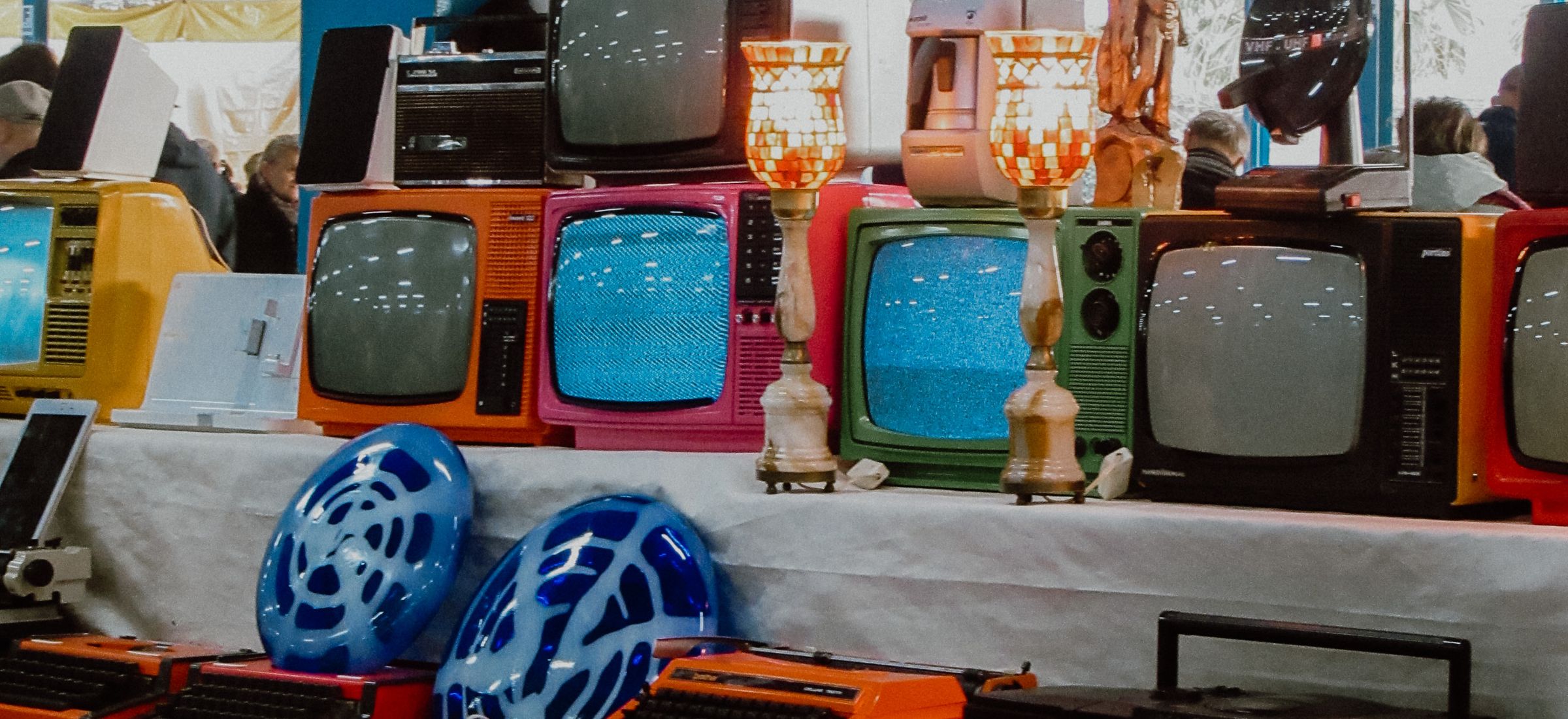 Colorful vintage TVs and electronics on display.